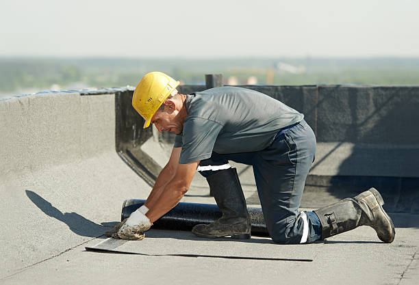 Roofer preparing part of bitumen roofing felt roll for melting by gas heater torch flame